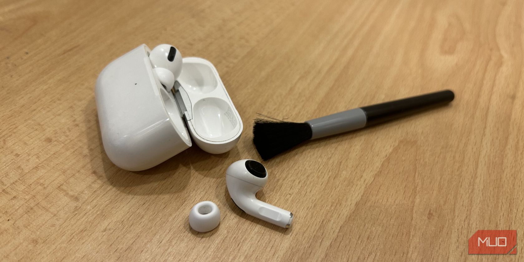 AirPods Pro on table with a cleaning brush.